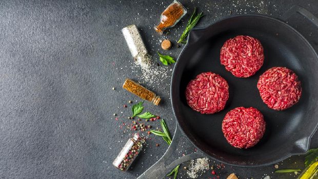 Raw minced meat beef burger cutlets. Cooking meat and burgers background with olive oil. herb, spices, black stone or concrete table, above, copy space