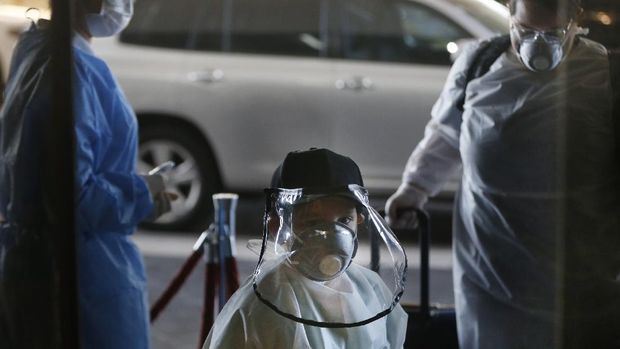 Wearing a face shield and face mask, Matias Morel and his aunt Stefanie Ruiz Diaz, right, pass a temperature check point upon arrival for a flight to Miami, Florida, from Silvio Pettirossi airport in Luque, on the outskirts of Asuncion, Paraguay, Thursday, April 23, 2020. Paraguay's government has organized with several other nations to get their nationals home, amid a lack of flights due to the global lockdown to contain the spread of the new coronavirus. (AP Photo/Jorge Saenz)