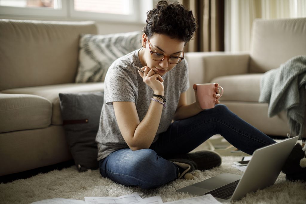 Woman sitting on sofa using laptop in her cozy loft apartment