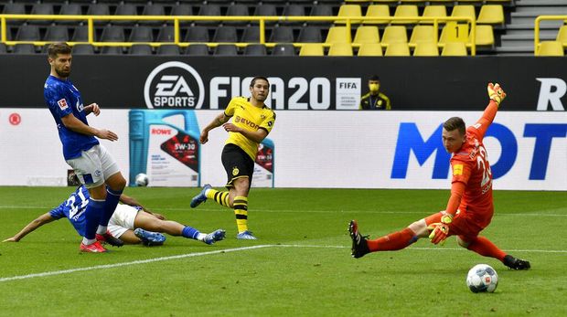 Dortmund's Raphael Guerreiro, center, scores his side's second goal during the German Bundesliga soccer match between Borussia Dortmund and Schalke 04 in Dortmund, Germany, Saturday, May 16, 2020. The German Bundesliga becomes the world's first major soccer league to resume after a two-month suspension because of the coronavirus pandemic. (AP Photo/Martin Meissner, Pool)