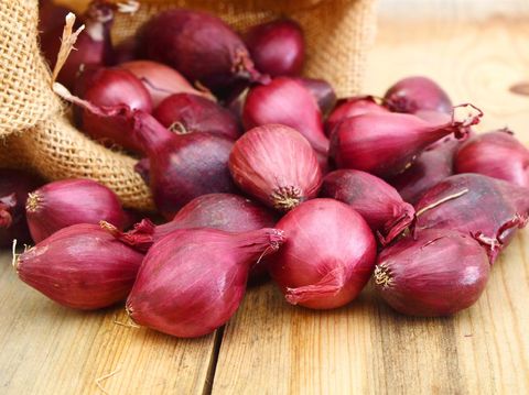 Red onions isolated in burlap on wooden background