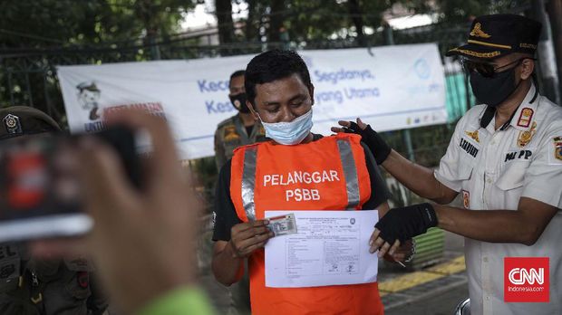 Seorang pelanggar Pembatasan Sosial Berskala Besar (PSBB) usai menerima sanksi di kawasan Terminal Kampung Melayu, Jakarta, Rabu, 20 Mei 2020. Sanksi kerja sosial seperti menyapu, menyiram tanaman sampai push-up diberlakukan bagi warga yang tak mengenakan masker saat beraktifitas di tempat umum. CNNIndonesia/Safir Makki
