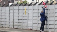 Seorang ayah menggendong anaknya untuk melihat para pemain Liverpool berlatih.