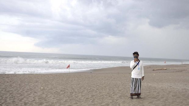 Pecalang berjaga di kawasan wisata Pantai Batu Belig di Badung yang ditutup sementara sebagai salah satu upaya untuk mencegah penyebaran COVID-19.