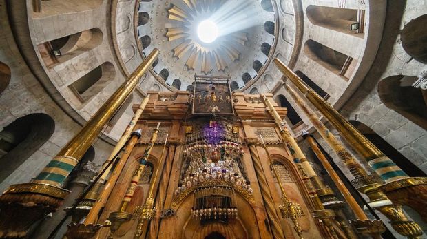 Lightbeam over the famous Aedicula - Jesus' Empty Tomb, where he is said to have been buried and resurrected - under the Church Dome Inside the famous Church of the Holy Sepulchre or Church of the Resurrection. It's the last station no. 14 representing the final episodes of Jesus' Passion of Via Dolorosa Christian Pilgrimage, Jerusalem, Israel, Middle East.