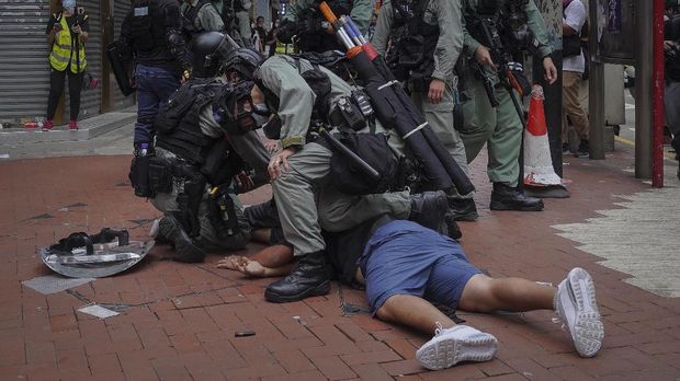 Riot police detain a protester during a demonstration against Beijing's national security legislation in Causeway Bay in Hong Kong, Sunday, May 24, 2020. Hong Kong police fired volleys of tear gas in a popular shopping district as hundreds took to the streets Sunday to march against China's proposed tough national security legislation for the city. (AP Photo/Vincent Yu)