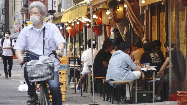 People have drink at a bar along a street in Tokyo Friday, May 15, 2020. While Tokyo is still under a coronavirus state of emergency, the pandemic is pitting those willing to follow requests for self-restraint against a sizable minority resisting the calls to stay home but eateries and pubs on backstreets are busy. (AP Photo/Eugene Hoshiko)