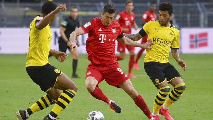 Borussia Dortmund vs Bayern Munich Munichs Robert Lewandowski, center, and Dortmunds Jadon Sancho, right, challenge for the ball during the German Bundesliga soccer match between Borussia Dortmund and FC Bayern Munich in Dortmund, Germany, Tuesday, May 26, 2020. The German Bundesliga is the worlds first major soccer league to resume after a two-month suspension because of the coronavirus pandemic. (Federico Gambarini/DPA via AP, Pool)