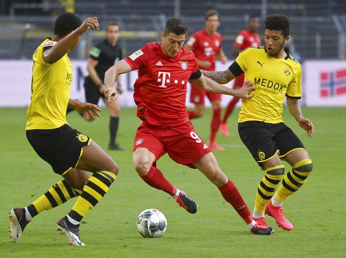Munichs Robert Lewandowski, center, and Dortmunds Jadon Sancho, right, challenge for the ball during the German Bundesliga soccer match between Borussia Dortmund and FC Bayern Munich in Dortmund, Germany, Tuesday, May 26, 2020. The German Bundesliga is the worlds first major soccer league to resume after a two-month suspension because of the coronavirus pandemic. (Federico Gambarini/DPA via AP, Pool)