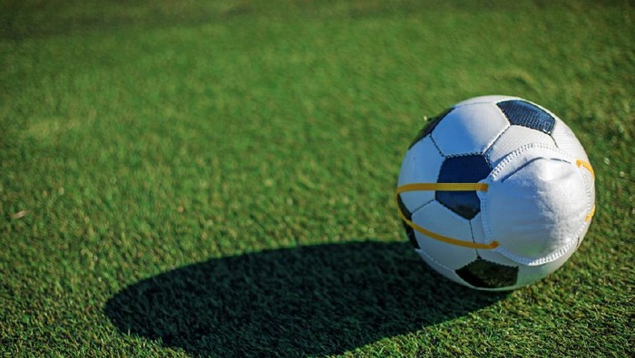 Soccer ball and virus mask to symbolise the delayed, postponed and cancelled Soccer and football competitions due to the corona Covid-19 virus outbreak