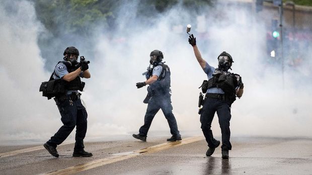 Kerusuhan di Minneapolis A police officer throws a tear gas canister towards protesters at the Minneapolis 3rd Police Precinct, following a rally for George Floyd on Tuesday, May 26, 2020, in Minneapolis. Four Minneapolis officers involved in the arrest of Floyd, a black man who died in police custody, were fired Tuesday, hours after a bystander's video showed an officer kneeling on the handcuffed man’s neck, even after he pleaded that he could not breathe and stopped moving. (Richard Tsong-Taatarii/Star Tribune via AP)
