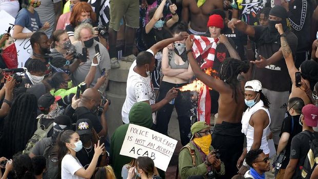 Protes Kematian George Floyd, Kantor CNN Dirusak Massa Demonstrators light an American flag on fire during a protest, Friday, May 29, 2020 in Atlanta. The protest started peacefully earlier in the day before demonstrators clashed with police. (AP Photo/Mike Stewart)