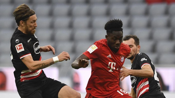 Bayerns Alphonso Davies, center, and  Duesseldorfs Kevin Stoeger challenge for the ball during the German Bundesliga soccer match between FC Bayern Munich and Fortuna Duesseldorf in Munich, Germany, Saturday, May 30, 2020. Because of the coronavirus outbreak all soccer matches of the German Bundesliga take place without spectators. (Christof Stache/Pool via AP)