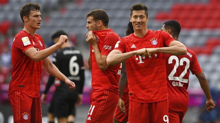 Munich players, from left, Benjamin Pavard, Lucas Hernandez and Robert Lewandowski, celebrate taking the score to  3:0 against Fortuna Dsseldorf, during their Bundesliga soccer match played without an audience in Munich, Germany, Saturday May 30, 2020. Soccer matches are being played without an audience because of the coronavirus pandemic. (Christof Stache/Pool via AP)