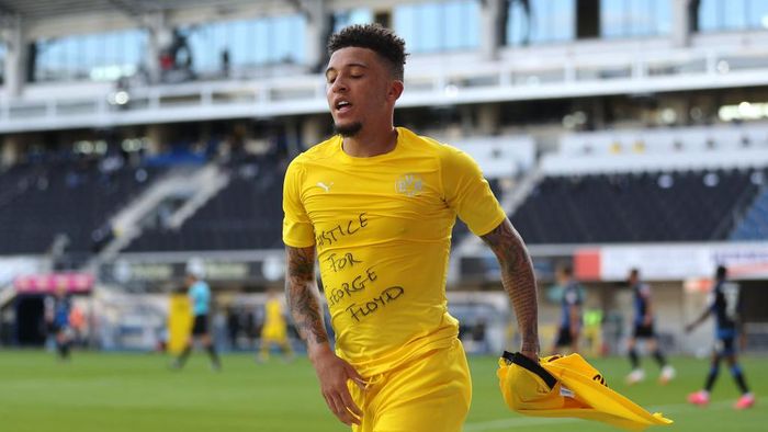 Jadon Sancho PADERBORN, GERMANY - MAY 31: Jadon Sancho of Borussia Dortmund celebrates scoring his teams second goal of the game with a Justice for George Floyd shirt during the Bundesliga match between SC Paderborn 07 and Borussia Dortmund at Benteler Arena on May 31, 2020 in Paderborn, Germany. (Photo by Lars Baron/Getty Images)