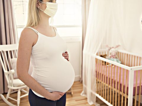 A pregnant woman wears a surgical mask to protect a COVID-19 (Coronavirus) and PM 2.5 and show a surgical mask on the abdomen to prevent infection to the fetus.