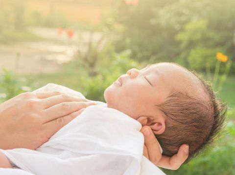 Baby sleeps on mother's hands and morning sun