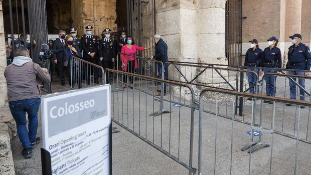 Alfonsina Russo, left wearing black face mask, director of the Colosseum Archaeological Park, opens the main entrance gate of Colosseum in Rome, Monday, June 1, 2020, reopening to the public one of Italy's most visited monument, after more of two months of lockdown for the coronavirus pandemics. The Colosseum, Palatine, Roman Forum and Domus Aurea reopens to the public on 1 June with some access restrictions for visitors. (AP Photo/Domenico Stinellis)