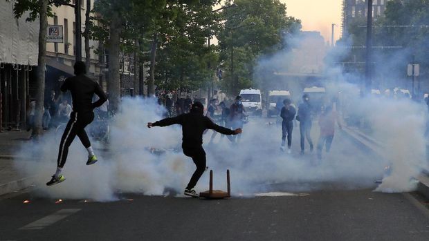 Protester kick in tear gas canisters during a demonstration Tuesday, June 2, 2020 in Paris. Thousands of people defied a police ban and converged on the main Paris courthouse for a demonstration to show solidarity with U.S. protesters and denounce the death of a black man in French police custody. The demonstration was organized to honor Frenchman Adama Traore, who died shortly after his arrest in 2016, and in solidarity with Americans demonstrating against George Floyd's death. (AP Photo/Michel Euler)