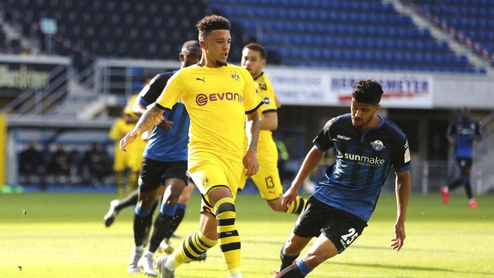 Dortmunds Jadon Sancho, left, battles for the ball with Paderborns Mohamed Drager during the German Bundesliga soccer match between SC Paderborn 07 and Borussia Dortmund at Benteler Arena in Paderborn, Germany, Sunday, May 31, 2020. Because of the coronavirus outbreak all soccer matches of the German Bundesliga take place without spectators. (Lars Baron/Pool via AP)