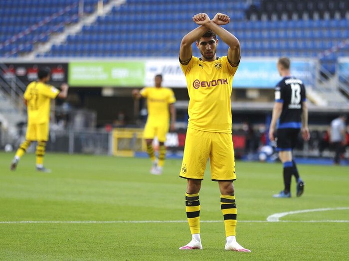 Achraf Hakimi Mouh of Borussia Dortmund celebrates scoring his teams fourth goal of the game during the German Bundesliga soccer match between SC Paderborn 07 and Borussia Dortmund at Benteler Arena in Paderborn, Germany, Sunday, May 31, 2020. Because of the coronavirus outbreak all soccer matches of the German Bundesliga take place without spectators. (Lars Baron/Pool via AP)
