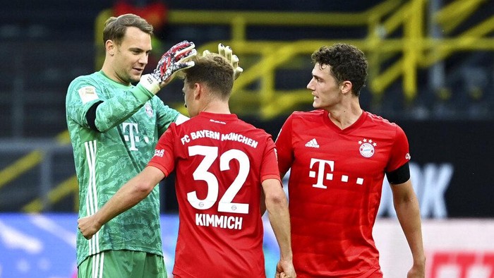 Munichs goalkeeper Manuel Neuer, left, and scorer Joshua Kimmich, center, celebrate after the German Bundesliga soccer match between Borussia Dortmund and FC Bayern Munich in Dortmund, Germany, Tuesday, May 26, 2020. The German Bundesliga is the worlds first major soccer league to resume after a two-month suspension because of the coronavirus pandemic. (Federico Gambarini/DPA via AP, Pool)