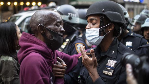 Momen Haru di Tengah Aksi Protes Kematian George Floyd di AS A protester and a police officer shake hands in the middle of a standoff during a solidarity rally calling for justice over the death of George Floyd Tuesday, June 2, 2020, in New York. Floyd died after being restrained by Minneapolis police officers on May 25. (AP Photo/Wong Maye-E)