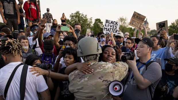 Momen Haru di Tengah Aksi Protes Kematian George Floyd di AS National Guard Master Sgt, Acie Matthews Jr. hugs a protester at the State Capitol in St. Paul, Minn., Monday, June 1, 2020, during protests over the death of George Floyd, who died May 25 after being restrained by Minneapolis police. (Carlos GonzalezStar Tribune via AP)