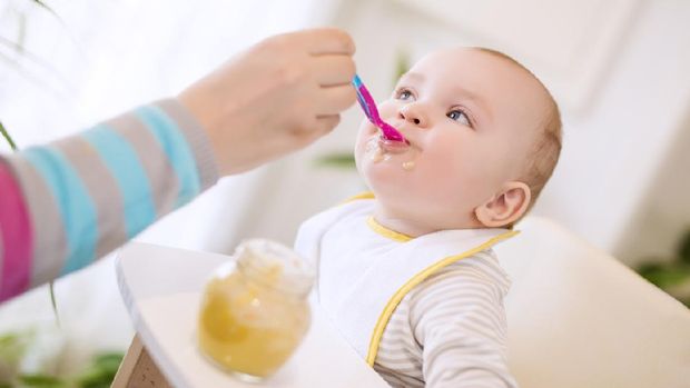 Close up of a mother feeding her baby in high chair