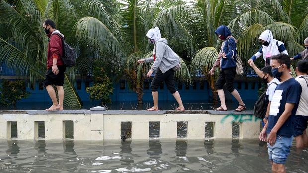 Warga meniti pagar menghindari banjir air rob di kawasan Muara Baru, Penjaringan, Jakarta Utara, Jumat (5/6/2020). Menurut Badan Meteorologi, Klimatologi, dan Geofisika (BMKG) rob disebabkan oleh kondisi pasang air laut yang cukup tinggi di beberapa wilayah Indonesia akibat fase bulan purnama. ANTARA FOTO/M Risyal Hidayat/wsj.