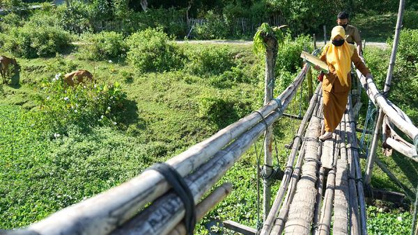 Potret Guru Lewati Jembatan Bambu untuk Antar Soal Ujian