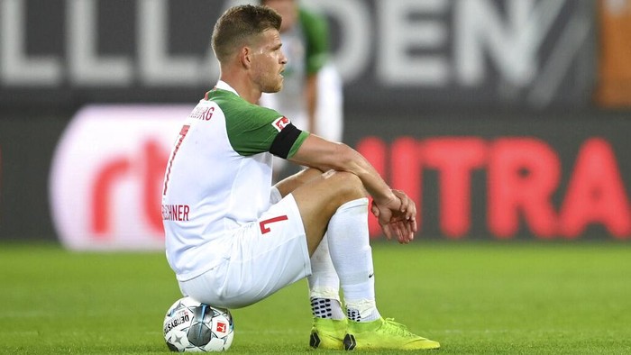 Augsburgs Florian Niederlechner sits on the ground after the German Bundesliga soccer match between FC Augsburg and SC Paderborn 07 in Augsburg, Germany, Wednesday, May 27, 2020. The German Bundesliga is the worlds first major soccer league to resume after a two-month suspension because of the coronavirus pandemic. (Matthias Hangst/Pool via AP)