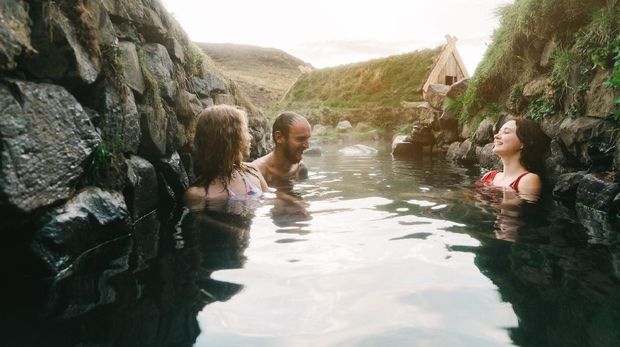 Young Caucasian friends taking bath in hot spring in Iceland