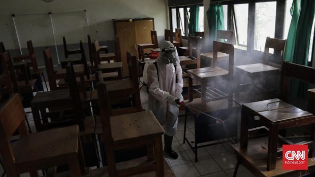 Anggota Palang Merah Indonesia menyemprotkan desinfektan dalam upaya menahan penyebaran virus corona di dalam ruang kelas di SMPN 139 dan SDN Malaka Jaya 04 Pagi. Jakarta, Selasa, 9 Juni 2020. (CNN Indonesia/ Adhi Wicaksono)