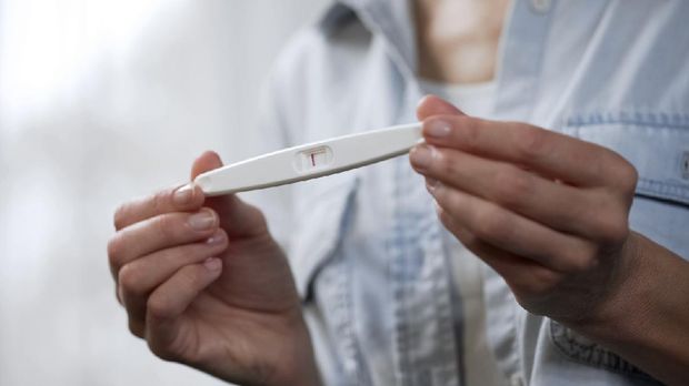 Female hands holding negative pregnancy test and showing it into camera, closeup