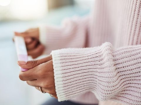 Young woman looking miserable staring at pregnancy test