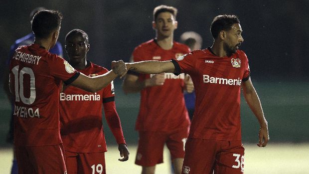Leverkusen's Karim Bellarabi, right,  celebrates after scoring his side's third goal during the German soccer cup, DFB Pokal, semi-final match between 1. FC Saarbruecken and Bayer 04 Leverkusen in Voelklingen, Germany, Tuesday, June 9, 2020. (Ronald Wittek/Pool Photo via AP)
