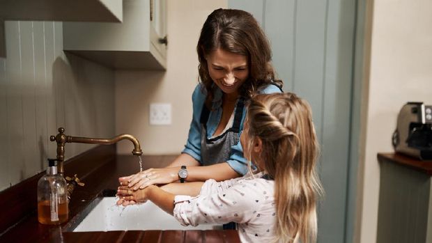 Cropped shot of a woman and her young daughter washing their hands in the kitchen at home