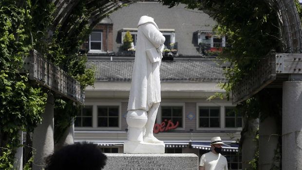 Patung Christopher Columbus Dirusak Passers-by walk near a damaged Christopher Columbus statue, Wednesday, June 10, 2020, in a waterfront park near the city's traditionally Italian North End neighborhood, in Boston. The statue was found beheaded Wednesday morning, Boston Mayor Marty Walsh said. (AP Photo/Steven Senne)