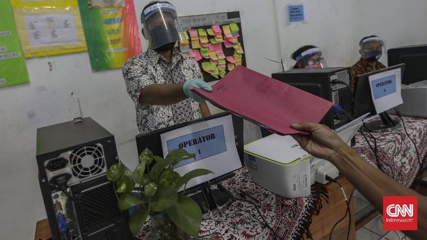 Petugas mempersiapkan fasilitas yang akan digunakan untuk penerimaan peserta didik baru (PPDB) di SMP Negeri 60 Jakarta, Kamis, 11 Juni 2020. Kementerian Pendidikan dan Kebudayaan (Kemendikbud) secara resmi menetapkan tahun ajaran baru 2020-2021 dimulai pada 13 Juli 2020. CNN Indonesia/Bisma Septalisma