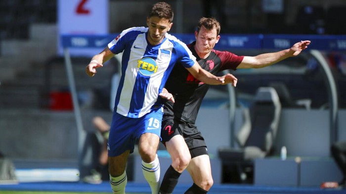 Hertha BSCs Marko Grujic in action with FC Augsburgs Stephan Lichtsteiner during the German Bundesliga soccer match between Hertha Berlin and Augsburg at the Olympiastadion in Berlin, Germany, Saturday, May 30, 2020. Because of the coronavirus outbreak all soccer matches of the German Bundesliga take place without spectators. (Hannibal Hanschke/pool photo via AP)