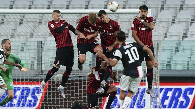 Juventus' Paulo Dybala performs a free-kick past AC Milan's wall , during an Italian Cup second leg soccer match between Juventus and AC Milan at the Allianz stadium, in Turin, Italy, Friday, June 12, 2020. The match was being played without spectators because of the coronavirus lockdown. (Spada/LaPresse via AP)