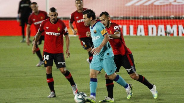 Barcelona's Lionel Messi, second right, vies for the ball with Mallorca's Joan Sastre, right, during the Spanish La Liga soccer match between Mallorca and FC Barcelona at Son Moix Stadium in Palma de Mallorca, Spain, Saturday, June 13, 2020. With virtual crowds, daily matches and lots of testing for the coronavirus, soccer is coming back to Spain. The Spanish league resumes this week more than three months after it was suspended because of the COVID-19 pandemic. (AP Photo/Francisco Ubilla)