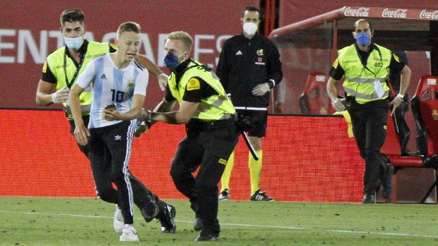 A supporter invades the pitch during the Spanish La Liga soccer match between Mallorca and FC Barcelona at Son Moix Stadium in Palma de Mallorca, Spain, Saturday, June 13, 2020. With virtual crowds, daily matches and lots of testing for the coronavirus, soccer is coming back to Spain. The Spanish league resumes this week more than three months after it was suspended because of the COVID-19 pandemic. (AP Photo/Francisco Ubilla)