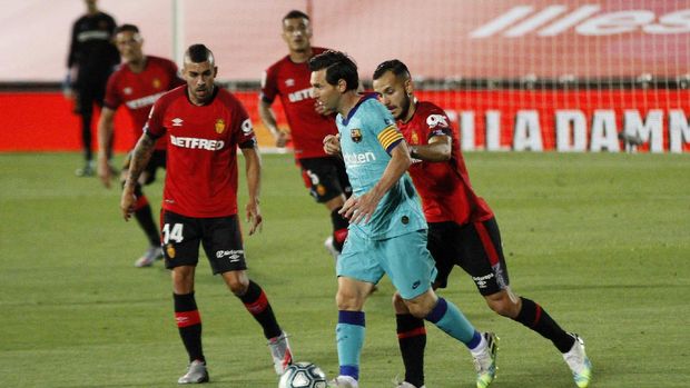 Barcelona's Lionel Messi, second right, vies for the ball with Mallorca's Joan Sastre, right, during the Spanish La Liga soccer match between Mallorca and FC Barcelona at Son Moix Stadium in Palma de Mallorca, Spain, Saturday, June 13, 2020. With virtual crowds, daily matches and lots of testing for the coronavirus, soccer is coming back to Spain. The Spanish league resumes this week more than three months after it was suspended because of the COVID-19 pandemic. (AP Photo/Francisco Ubilla)