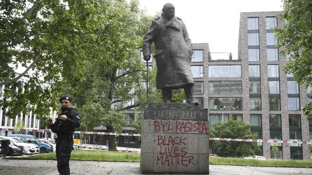 Patung Winston Churchill A police officer stands next to a statue of former British prime minister Winston Churchill in Prague, Czech Republic, Thursday, June 11, 2020. On the plinth of the statue unknowns sprayed that Churchill was a racist. It is also written 'Black Lives Matter' there. The slogans may have been written in a reference to the ongoing protests after the death of African American George Floyd in a police action in the U.S. city of Minneapolis. (Michal Kamaryt/CTK via AP)