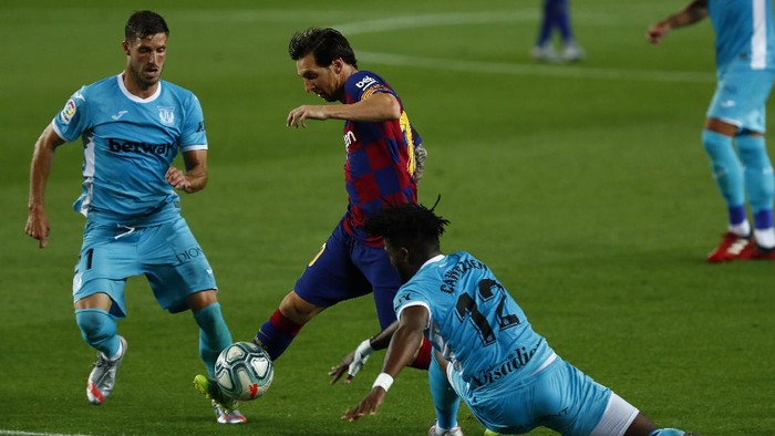 Barcelonas Lionel Messi, center, vies for the ball with Leagnes Chidozie Awaziem, right, and Leganes Ruben Perez during the Spanish La Liga soccer match between FC Barcelona and Leganes at the Camp Nou stadium in Barcelona, Spain, Tuesday, June 16, 2020. (AP Photo/Joan Montfort)