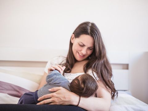Young mother breastfeeding her baby boy in the bedroom. Belgrade, Serbia