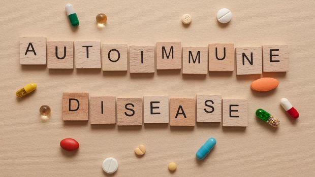 The word autoimmune disease formed with wooden letters and pills around