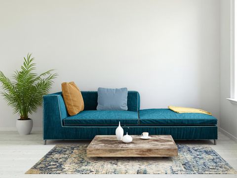 Posters on grey wall above white cupboard in bright living room interior with sofa and carpet. Real photo